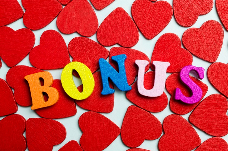 Wooden letters in different colors spelling Bonus on a background of red wooden hearts